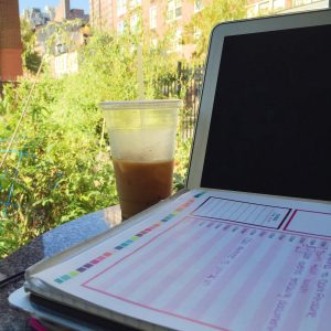 to do list sits atop computer, which is next to a large window on a bright sunny day