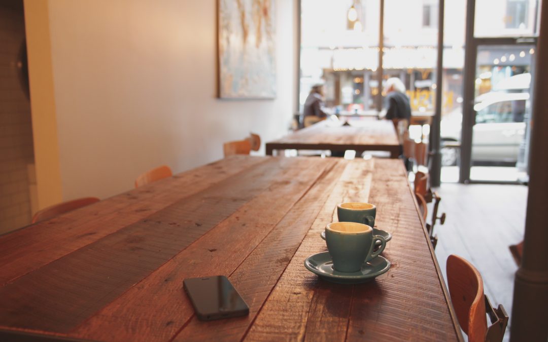 two coffees and a cell phone on a table in a coffeeshop