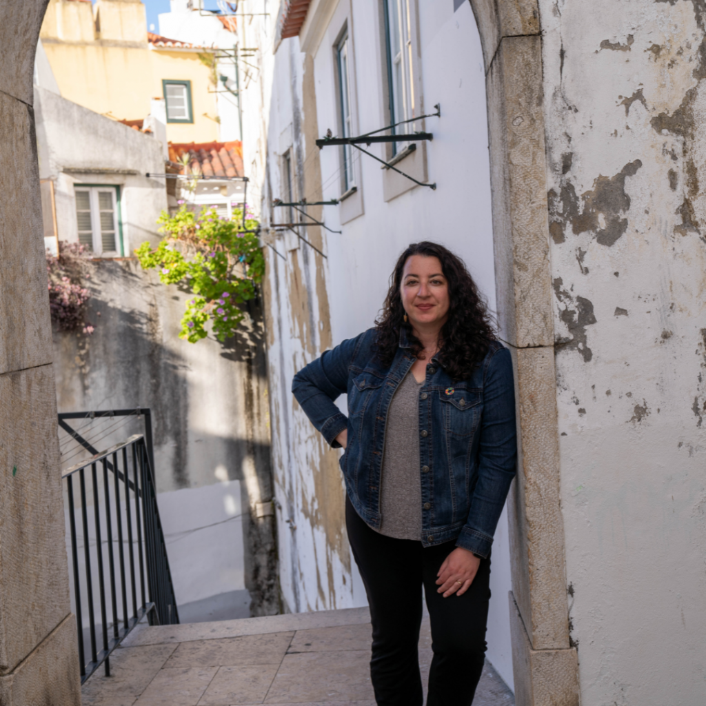 A woman leaning against an outdoor archway.